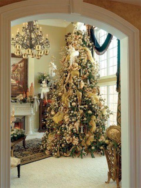 Living room fireplace mantel styled with rich evergreen garland, brass candle holders, and warm glow.