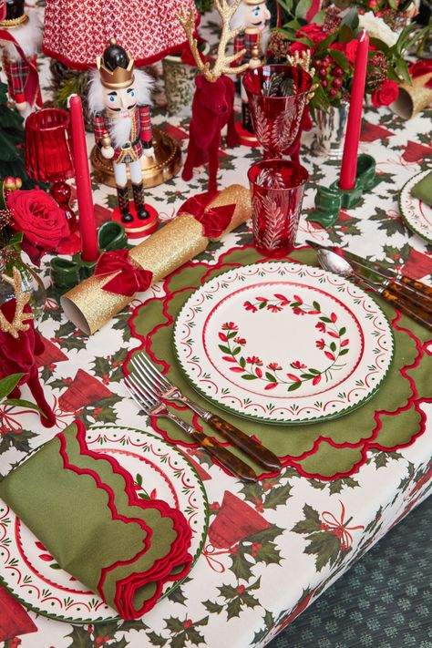 Farmhouse dining room with wreath-patterned china, plaid textiles, natural wood table, warm string lights.