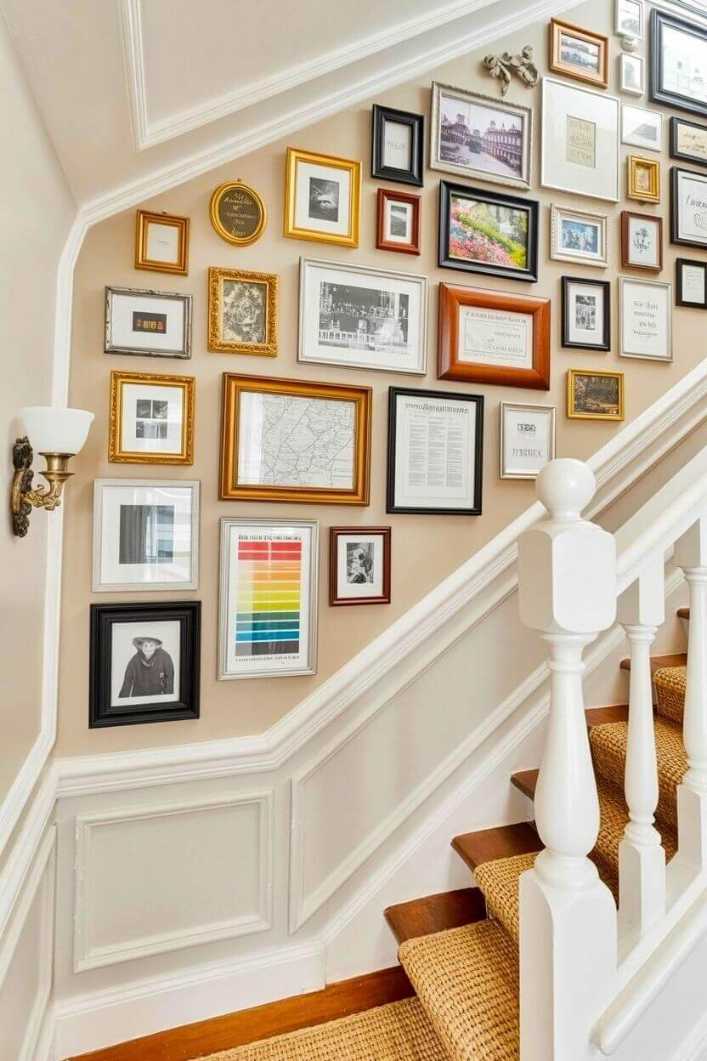 Staircase wall with vintage gold frames, black and white photos, and warm gallery lighting