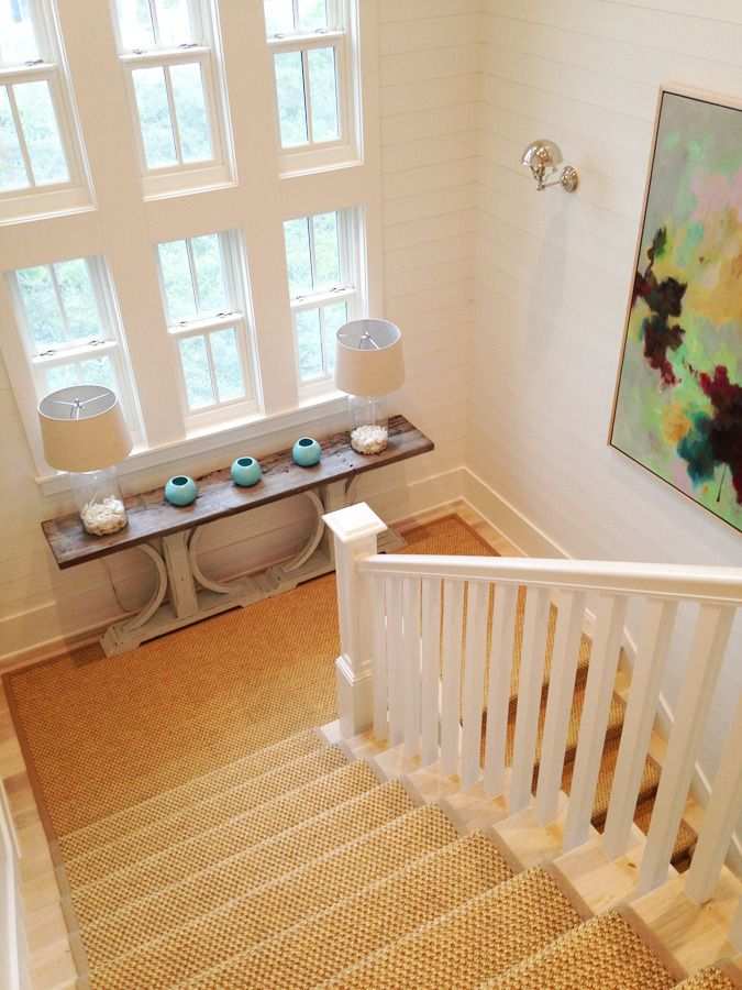 Cozy stair landing with armchair, side table, lamp, and rug, warm lighting