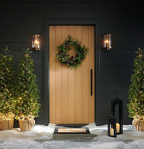 Entrance door with a single, simple eucalyptus wreath, matte black hardware, warm porch light.
