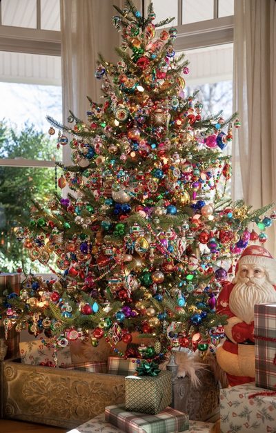 Front door entrance adorned with a large frosted eucalyptus and white berry wreath christmas decorating trends.