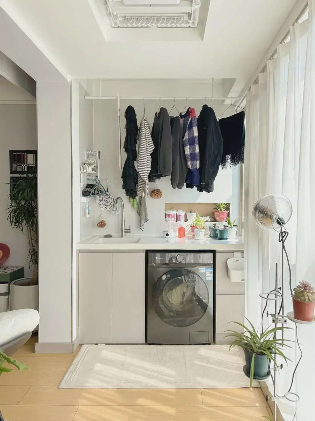 Modern small apartment laundry space with deep charcoal cabinets Carrara marble backsplash and brass fixtures