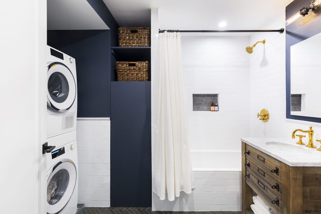 Industrial small apartment laundry nook with black iron pipe shelving reclaimed wood concrete look tiles