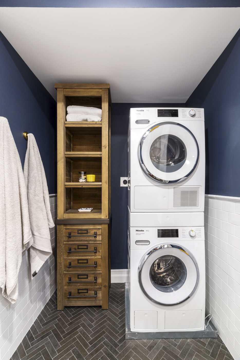 Coastal apartment laundry hallway featuring navy blue cabinets bright white subway tile and nickel hardware