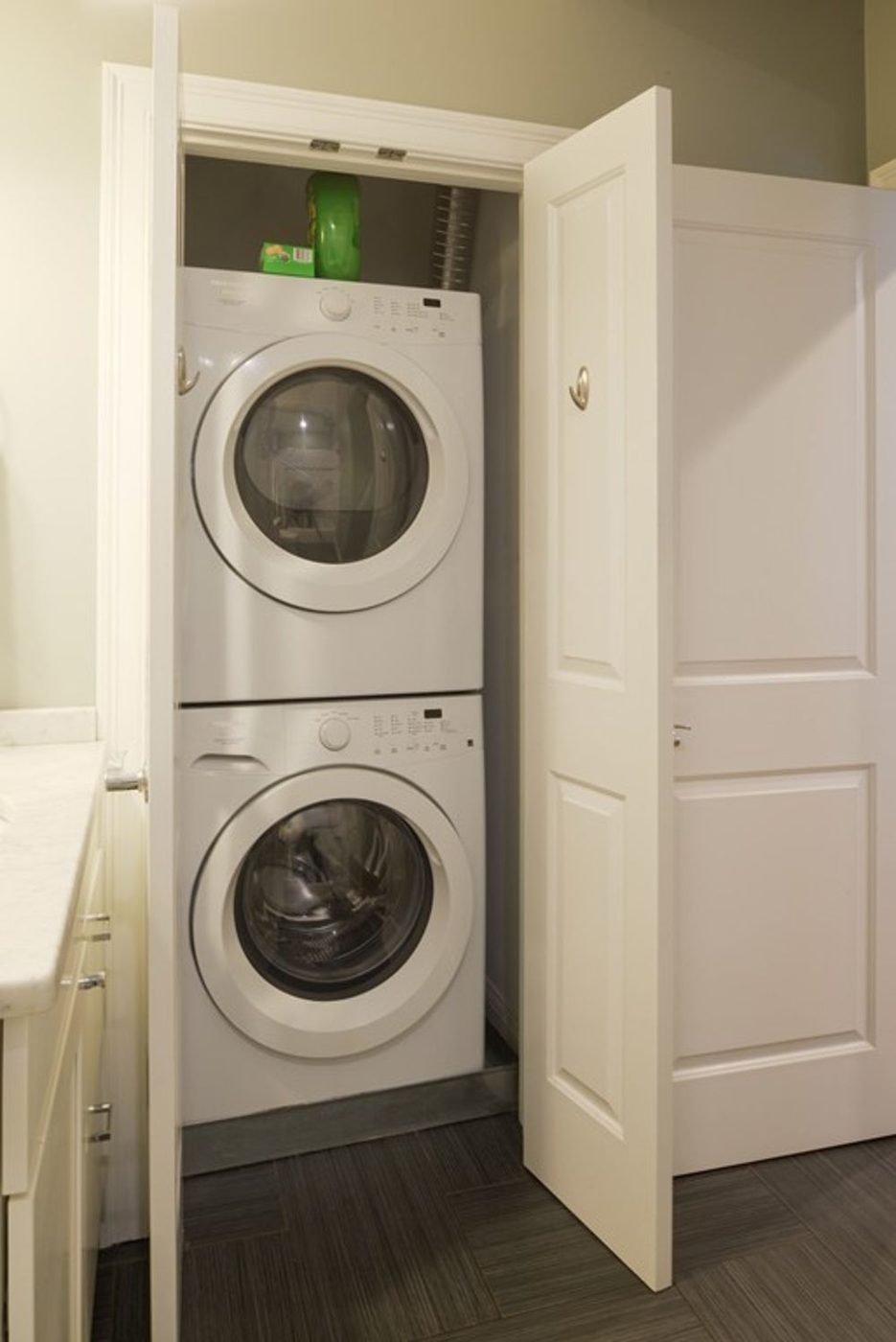 Micro apartment laundry nook painted warm terracotta with floating brass shelves and stackable bamboo bins