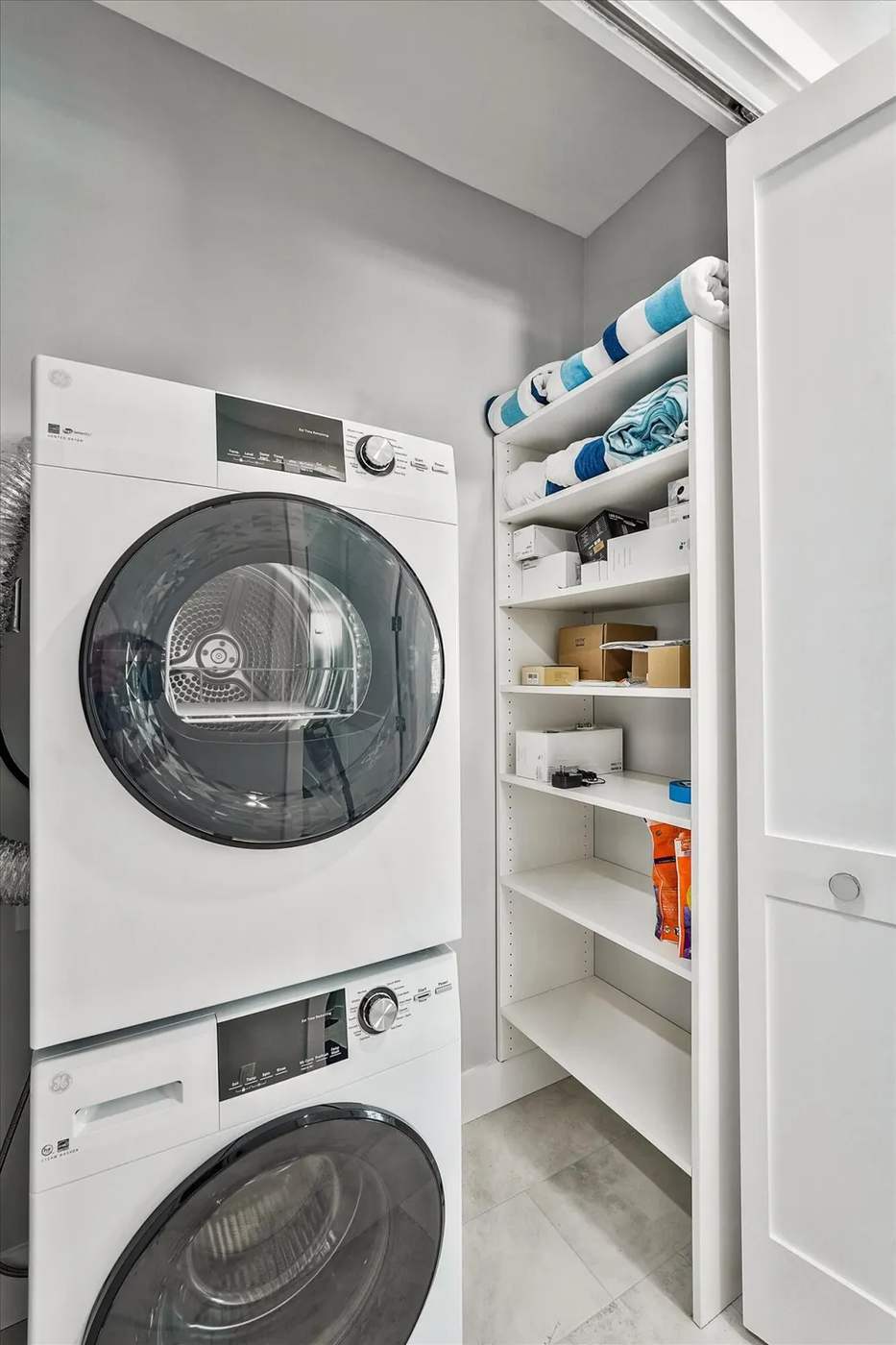 Compact apartment laundry zone with terrazzo tiles, navy blue built-in cabinets, and warm globe pendant lighting.