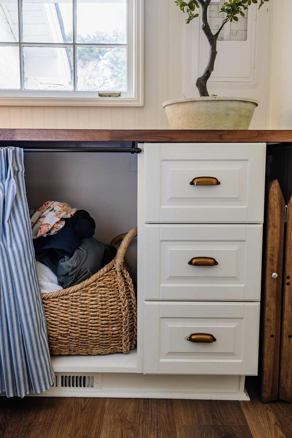 Modern farmhouse laundry nook with white apron sink, matte black hardware, vertical shiplap walls.