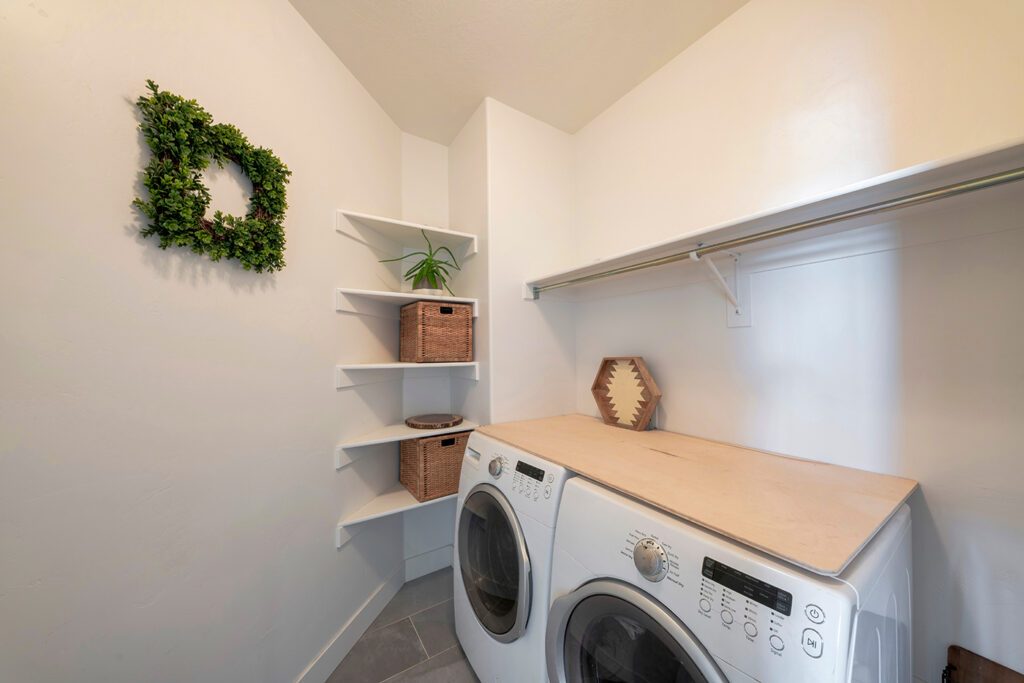 Bohemian style laundry space featuring colorful terrazzo tile backsplashes, cane webbing cabinets, rattan accessories.