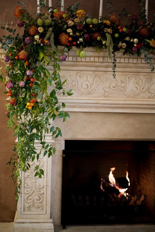 Modern living room mantel featuring trailing eucalyptus pine garland, white oak details, and soft lighting.