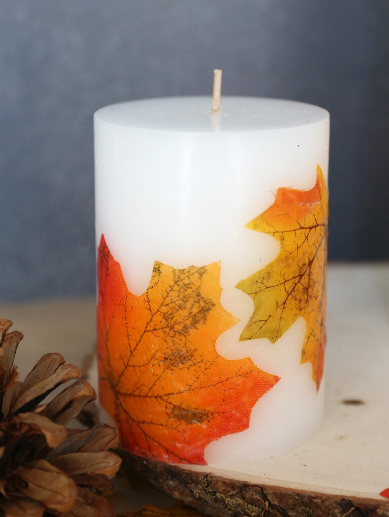 Close‑up of pillar candle, leaf decoupage, brushed metal, soft evening lighting in a den