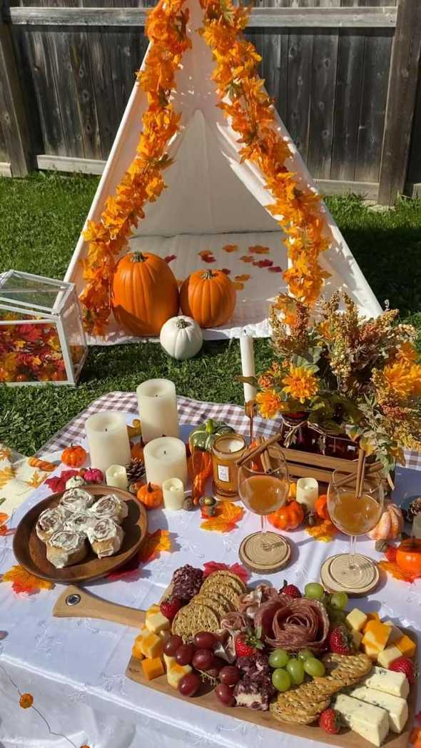 Outdoor backyard teepee with woven walls, plaid cushions, string lights, wooden floor, autumn décor