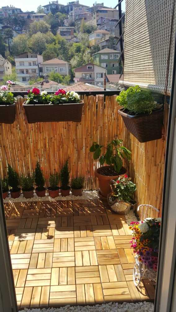 Balcony privacy screen made of bamboo reed panels and reclaimed wood tiles, creating a secluded nook.