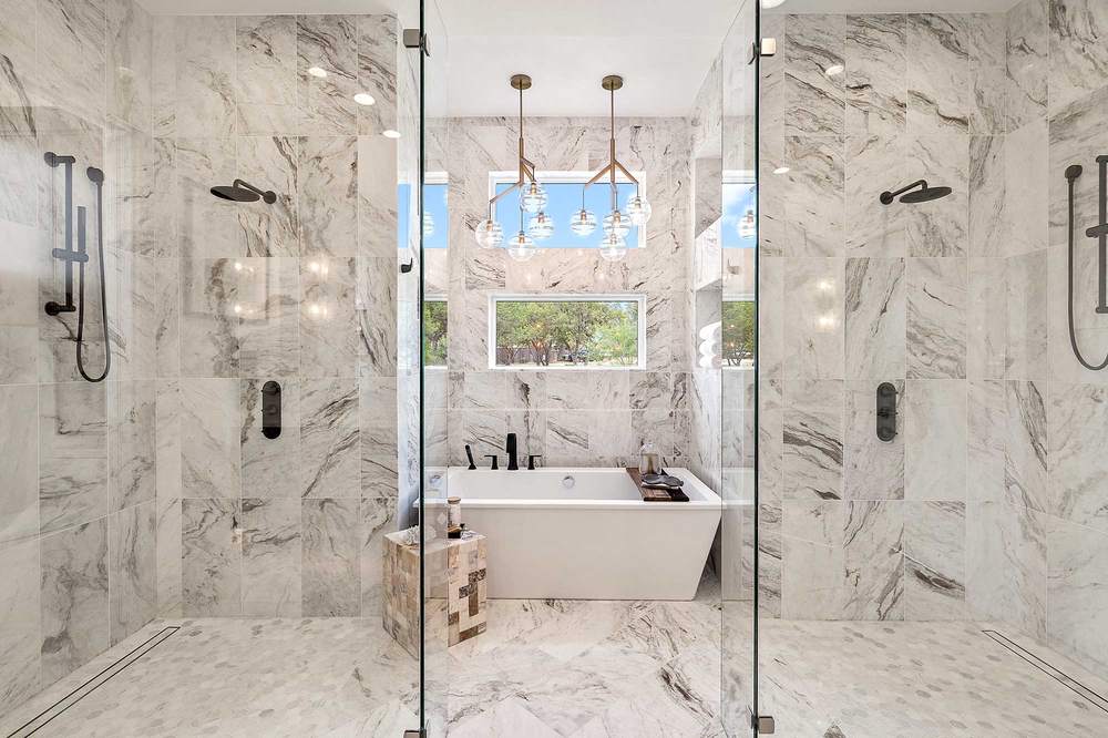 Luxury modern bathroom with matte white freestanding tub warm limestone flooring ambient golden bath backlight.