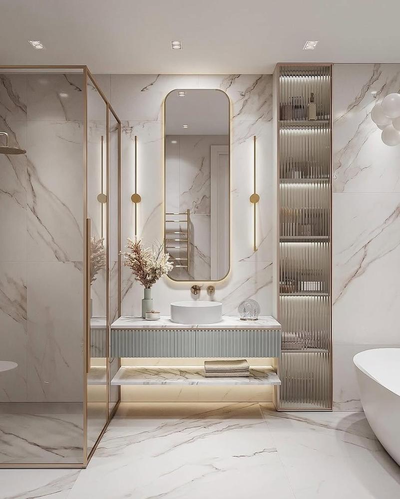 Monolithic stone double trough sink wall mounted bronze faucets fluted timber vanity warm ambient wall lights.