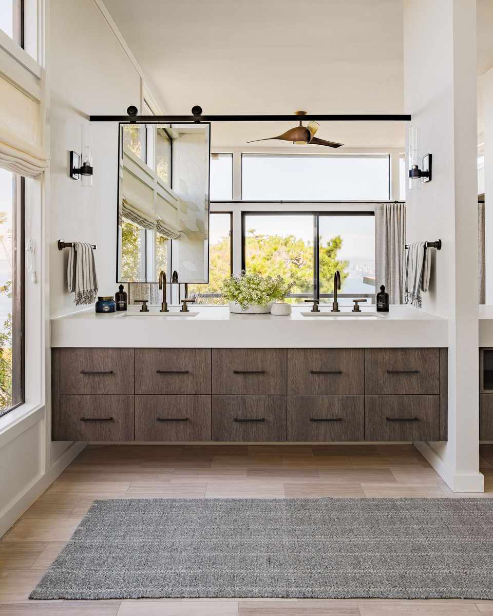 Scandinavian bathroom with a frameless round mirror, light oak vanity, and matte black fixtures.