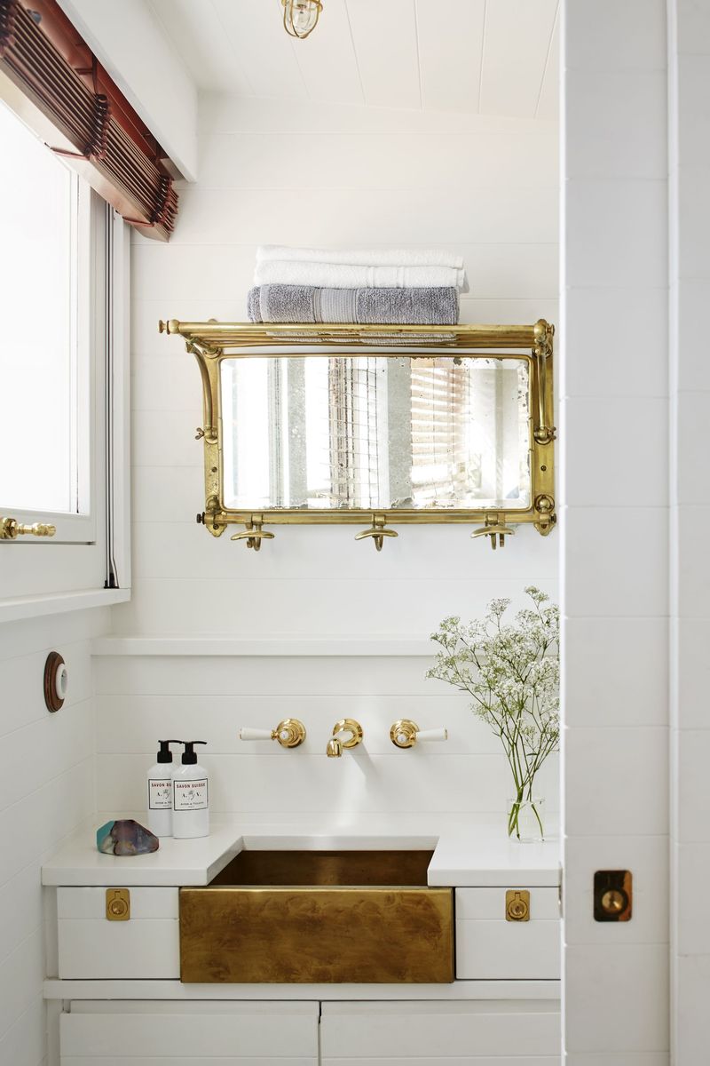Eclectic bathroom with a heavy ornate gold mirror, pedestal sink, and floral wallpaper.