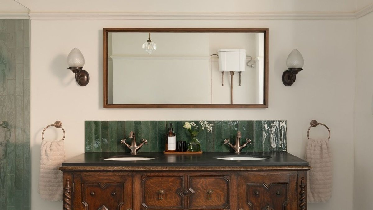 Spacious bathroom with a large leaning mirror, potted plant, and woven rug.