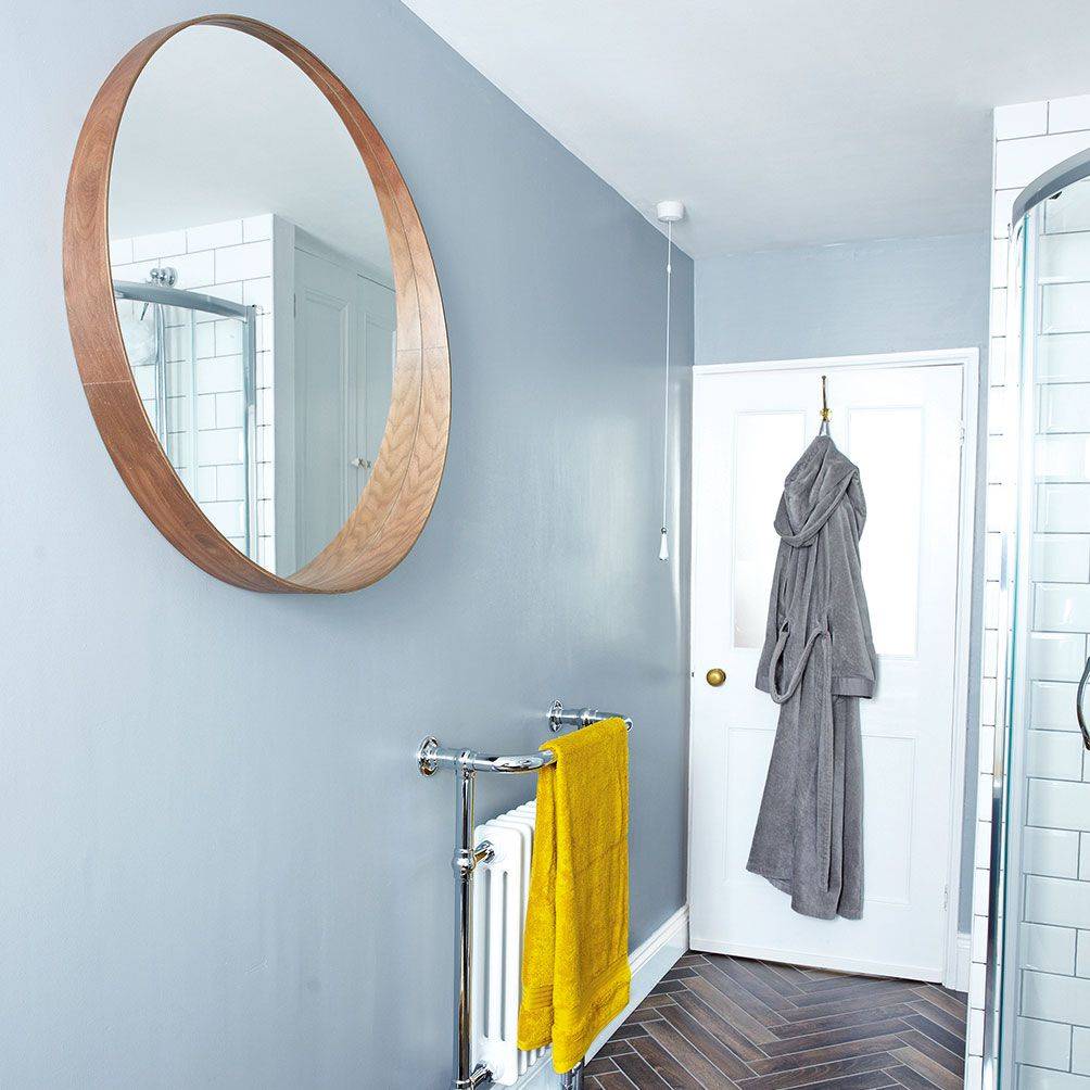 Minimalist bright bathroom with a white frame mirror, light wood accents, and bright lighting.