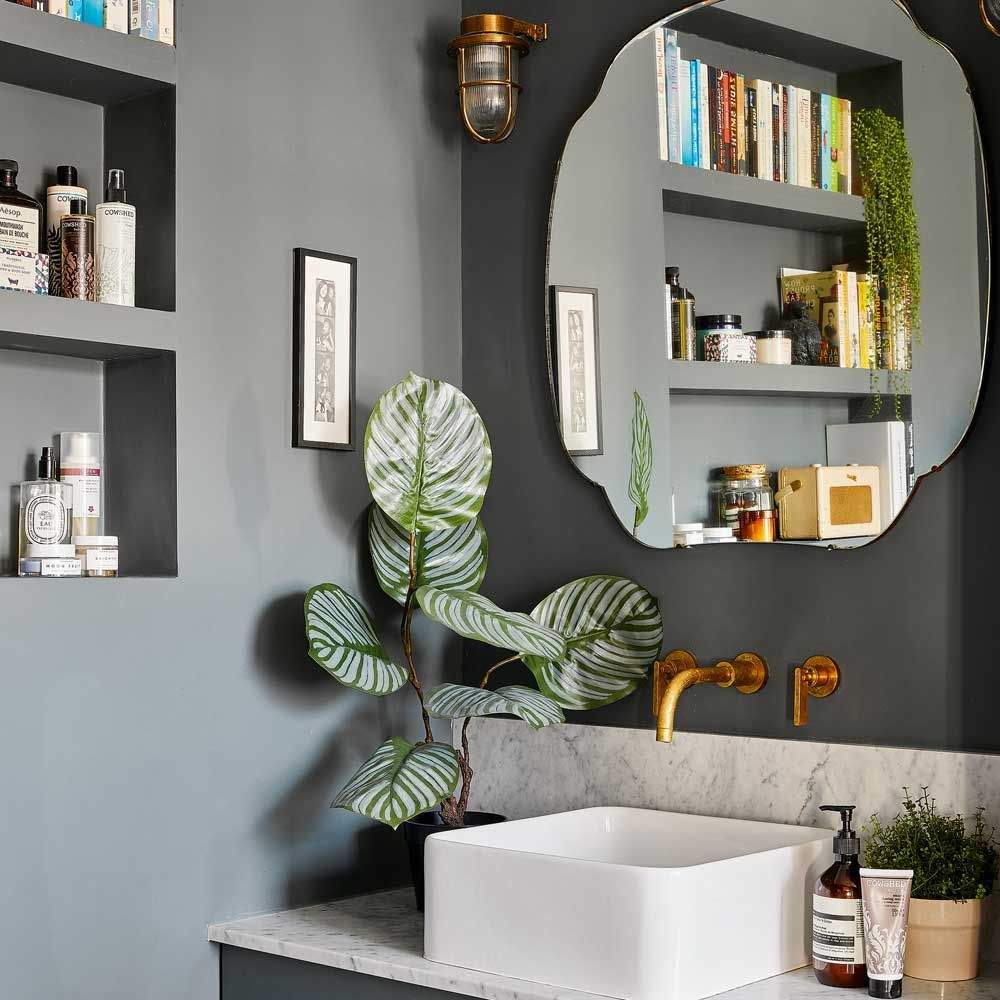 Dressing-style bathroom with a three-part folding mirror, vanity stool, and gold fixtures.