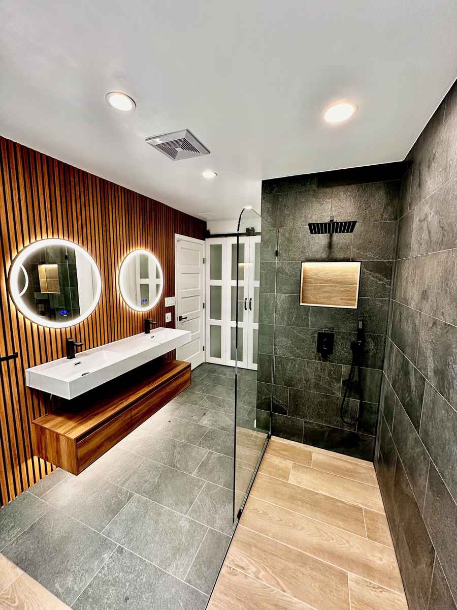 A polished chrome oval mirror that swivels on a wall-mounted bracket in a bathroom.