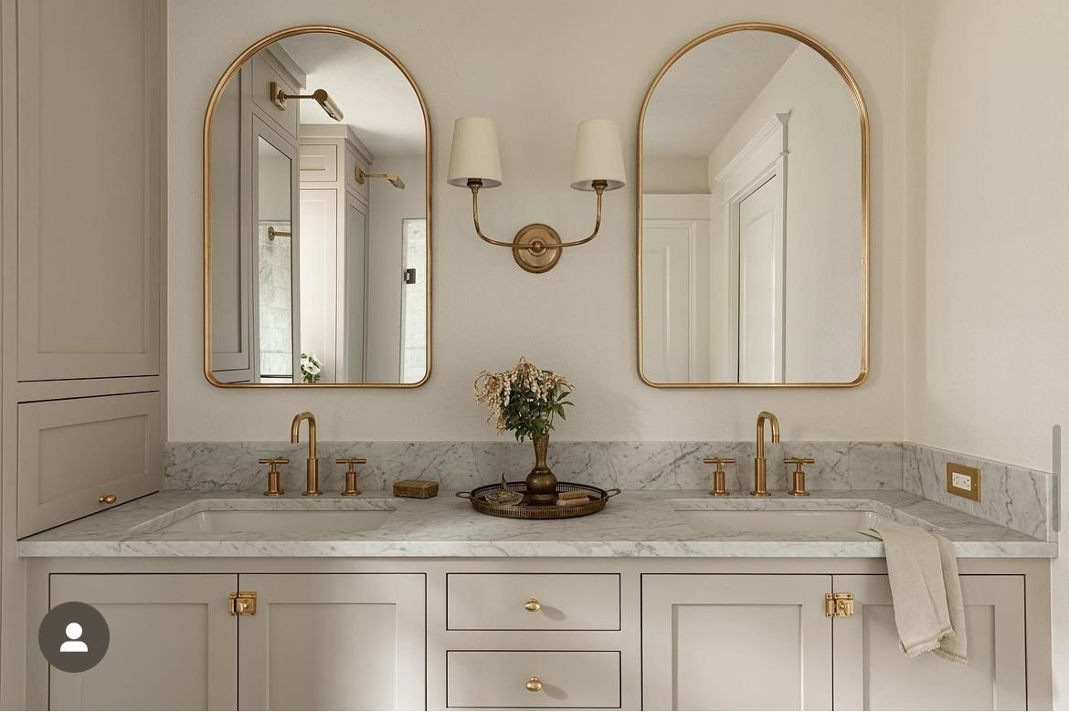 A rectangular mirror with a thick matte white frame in a bright bathroom.