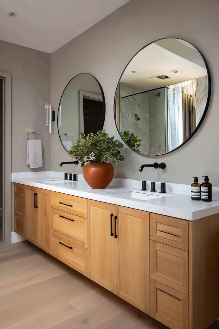 A round mirror with a hammered copper frame above a dark granite countertop.