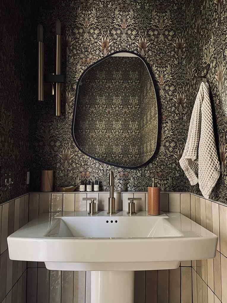A trendy bathroom mirror with delicate scalloped edges above a soft pink vanity.