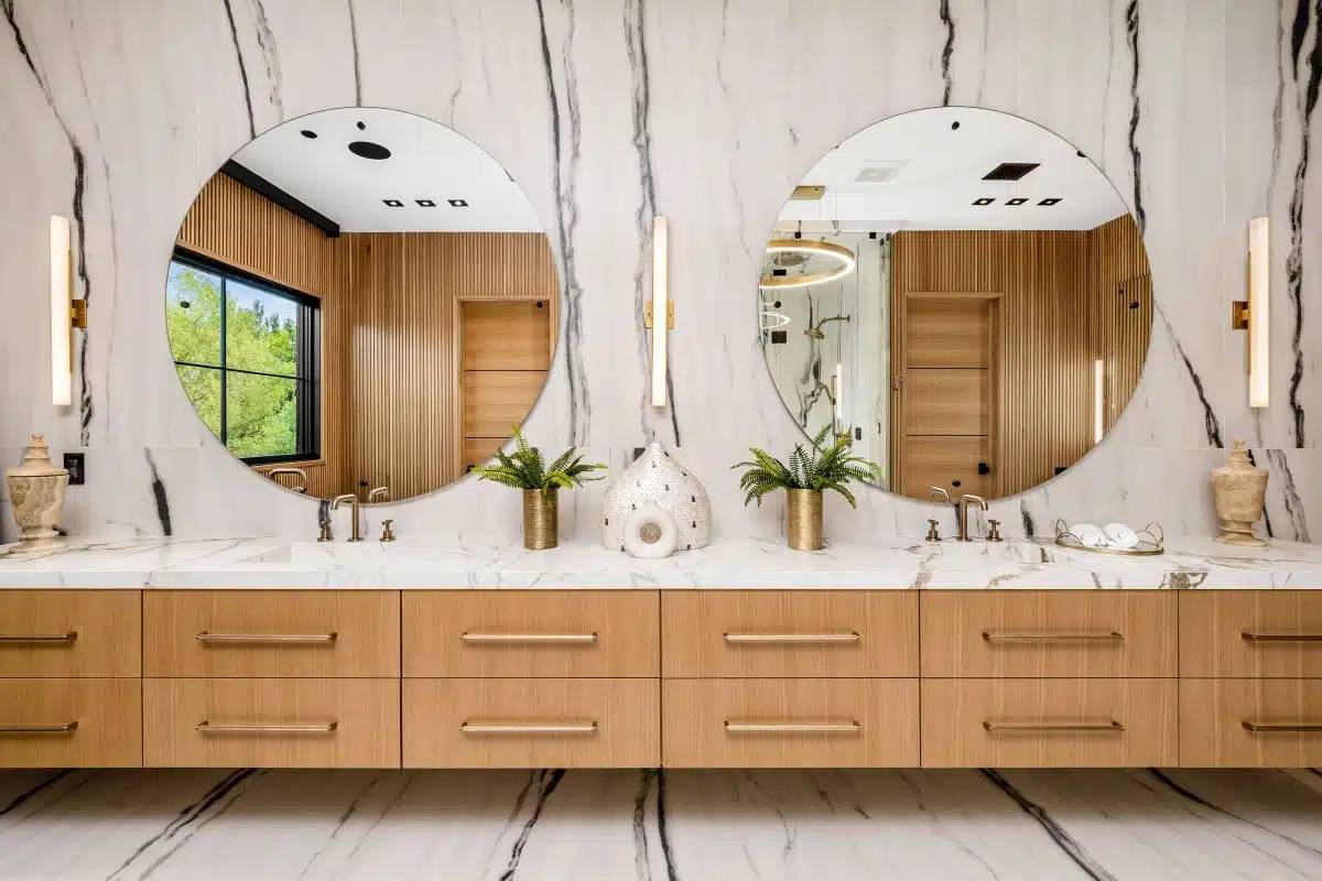 A square mirror framed by black plumbing pipes in an urban industrial bathroom.