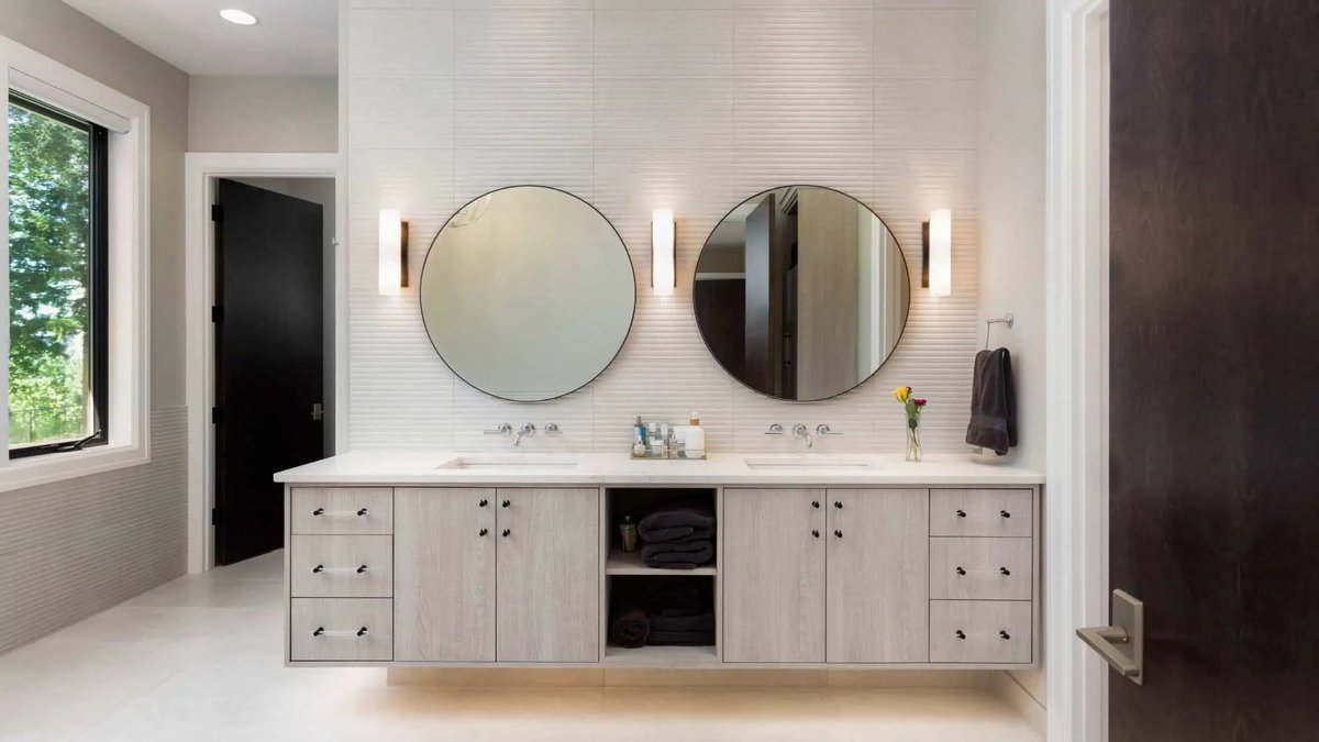 A large frameless mirror with wide beveled glass edges above a marble vanity.
