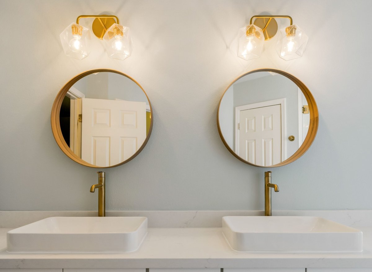 A round mirror with a woven rattan frame in a natural, boho-style bathroom.