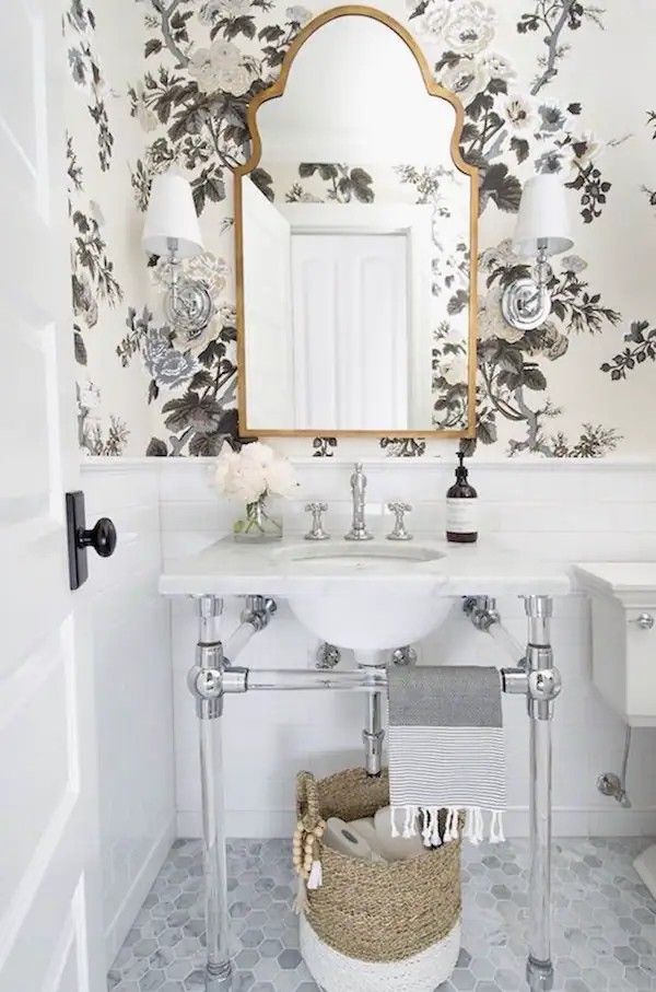Elegant bathroom with black white botanical wallpaper vintage ornate gold mirror soft vanity lighting.