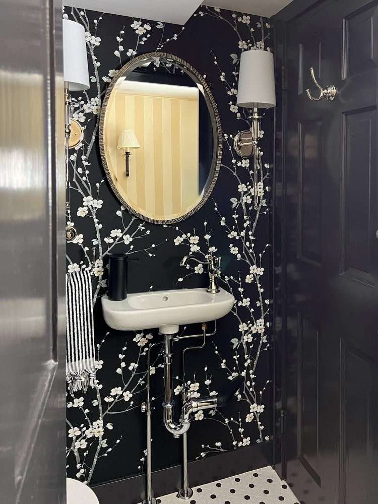 Luxury bathroom with black white floral wallpaper white freestanding soaking tub soft recessed lighting.