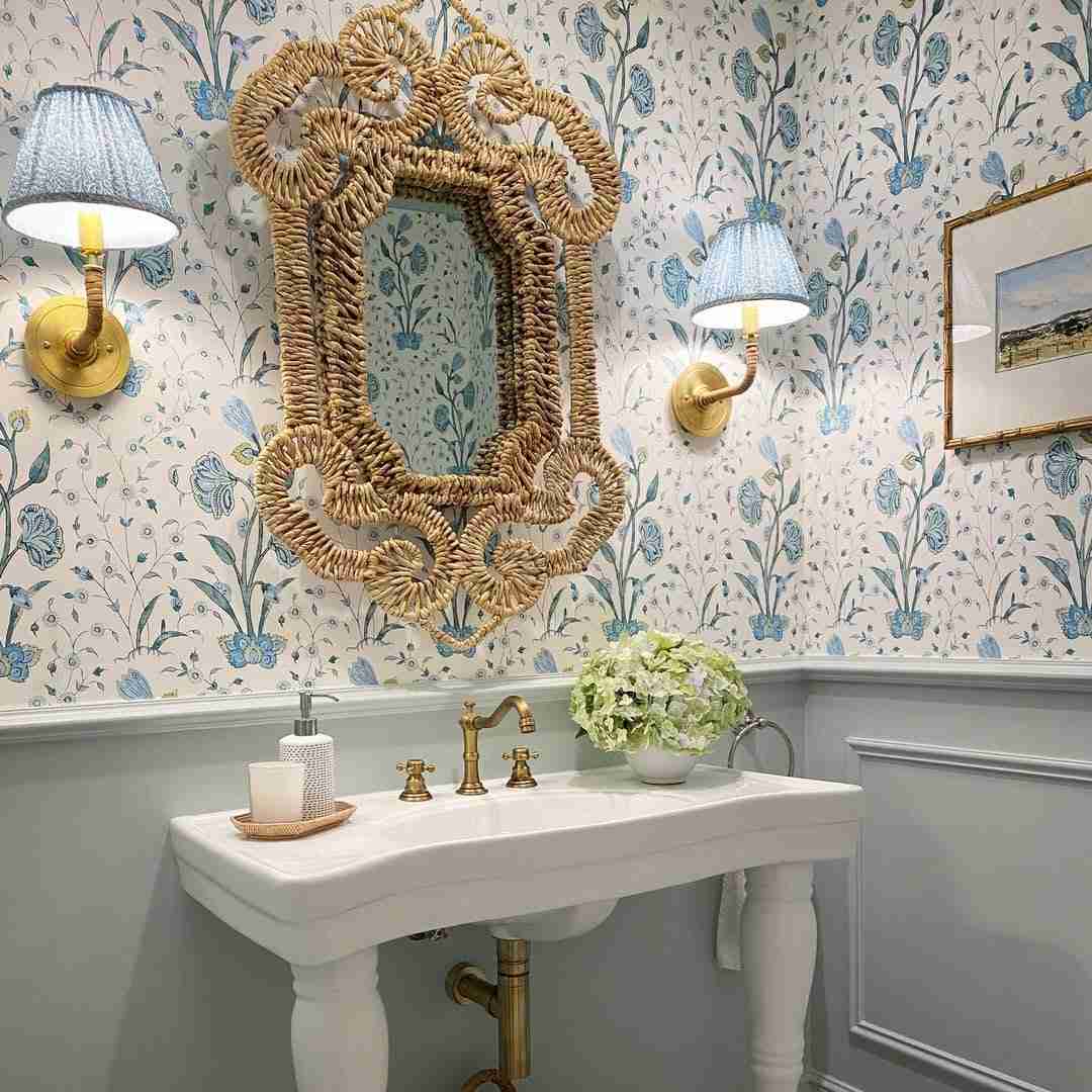 Traditional powder room with blue floral wallpaper carved ornate gold mirror brass vanity sconce.