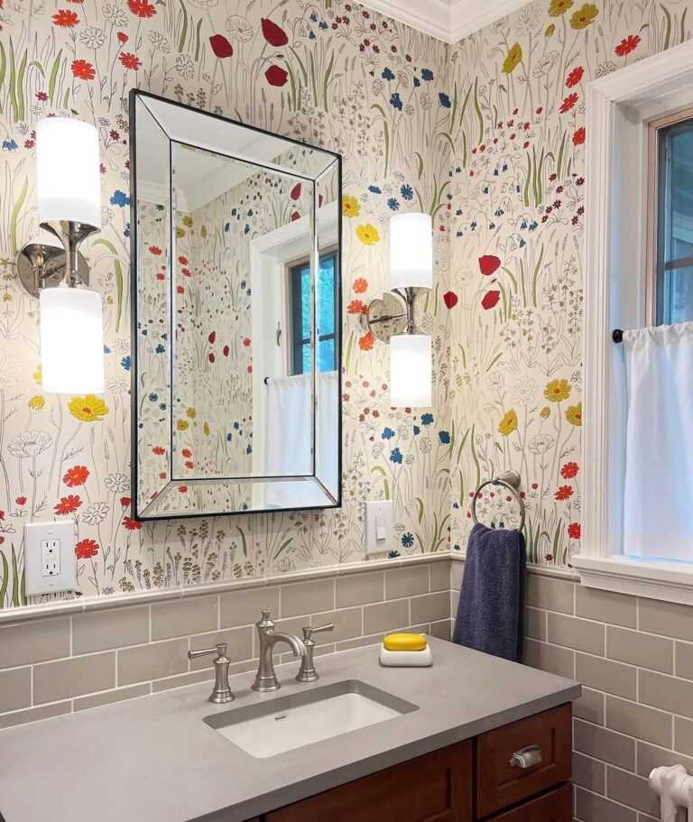Maximalist bathroom featuring colorful floral wallpaper wood vanity cabinet warm overhead globe light.
