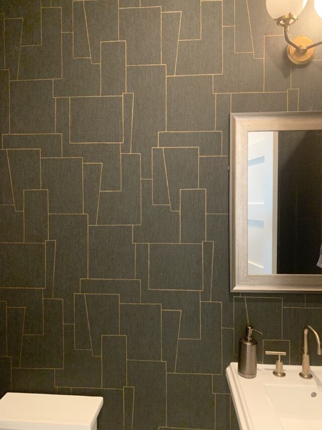 Dark modern bathroom with charcoal geometric wallpaper marble vanity unit sleek brass sconces.