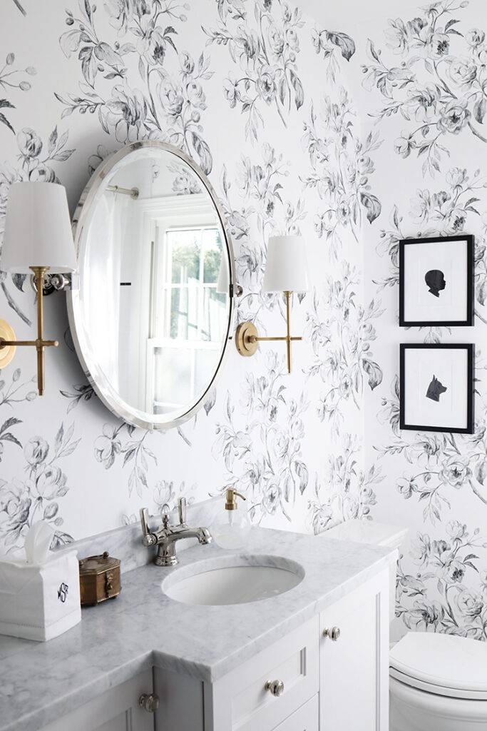 Minimalist bathroom with gray floral wallpaper sleek oval mirror light wood vanity unit.