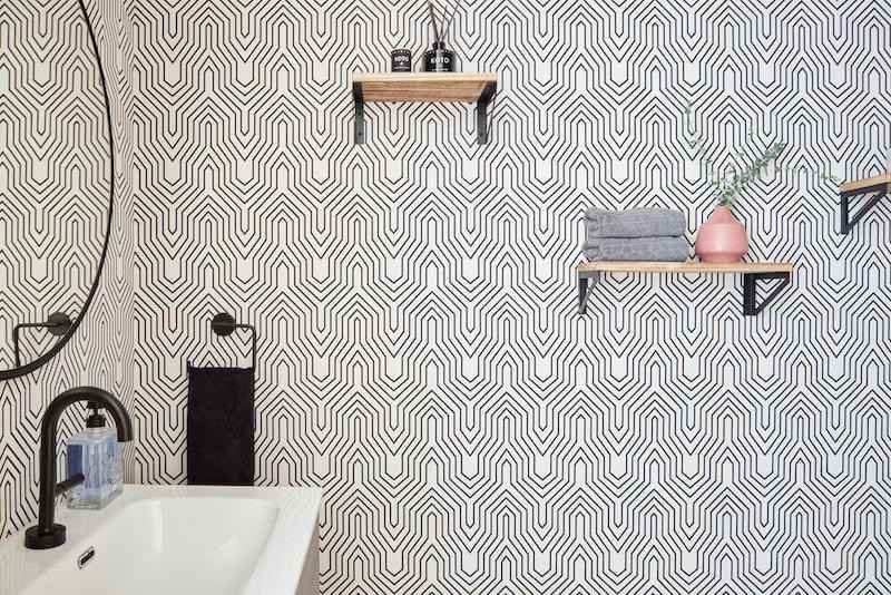 Minimalist gray patterned wallpaper in a sleek modern bathroom with neutral stone surfaces.