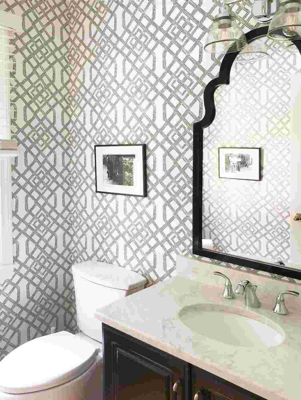 Traditional gray trellis wallpaper in a bright bathroom with white trim and vanity.