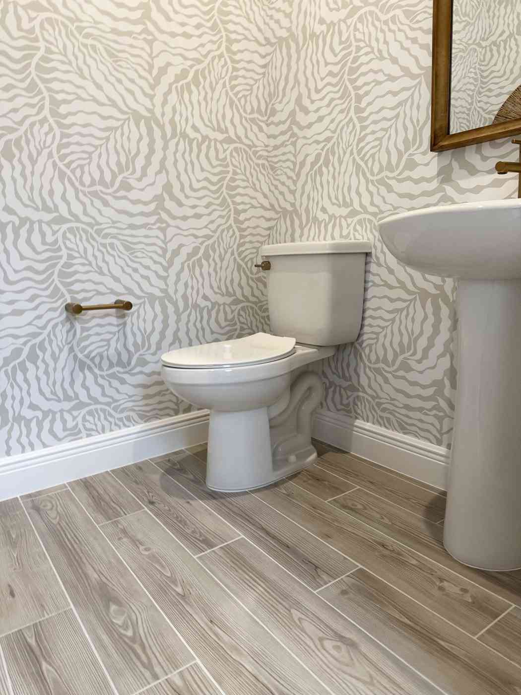 Contemporary bathroom with organic wavy gray wallpaper and sleek white fixtures.