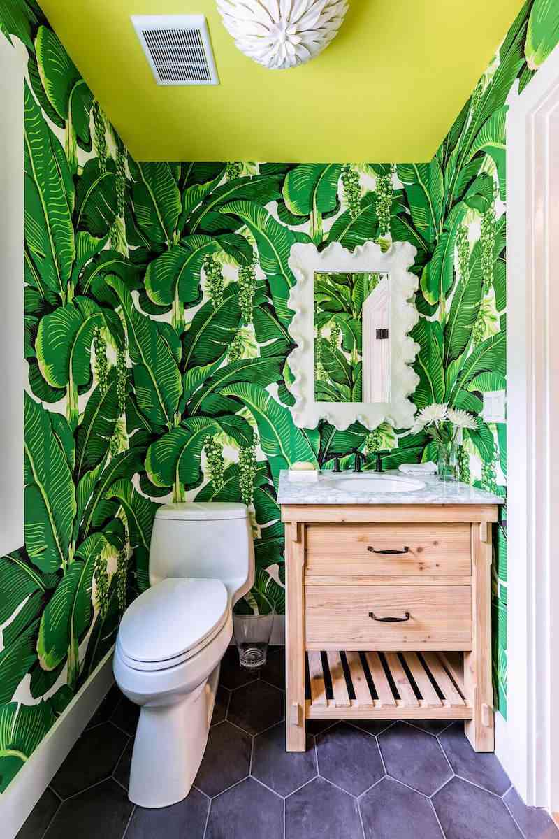 Bold green banana leaf wallpaper in a vibrant powder room with tropical vibes.
