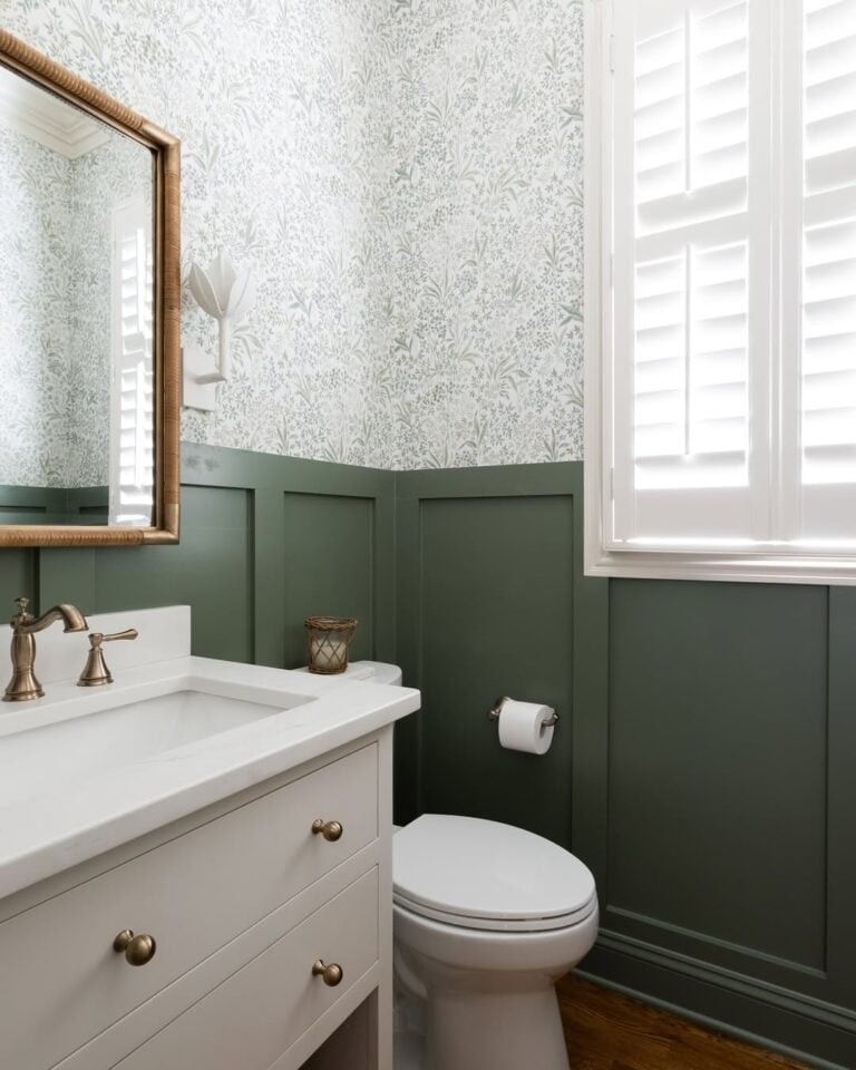 A charming powder room with green and white patterned wallpaper and classic fixtures.