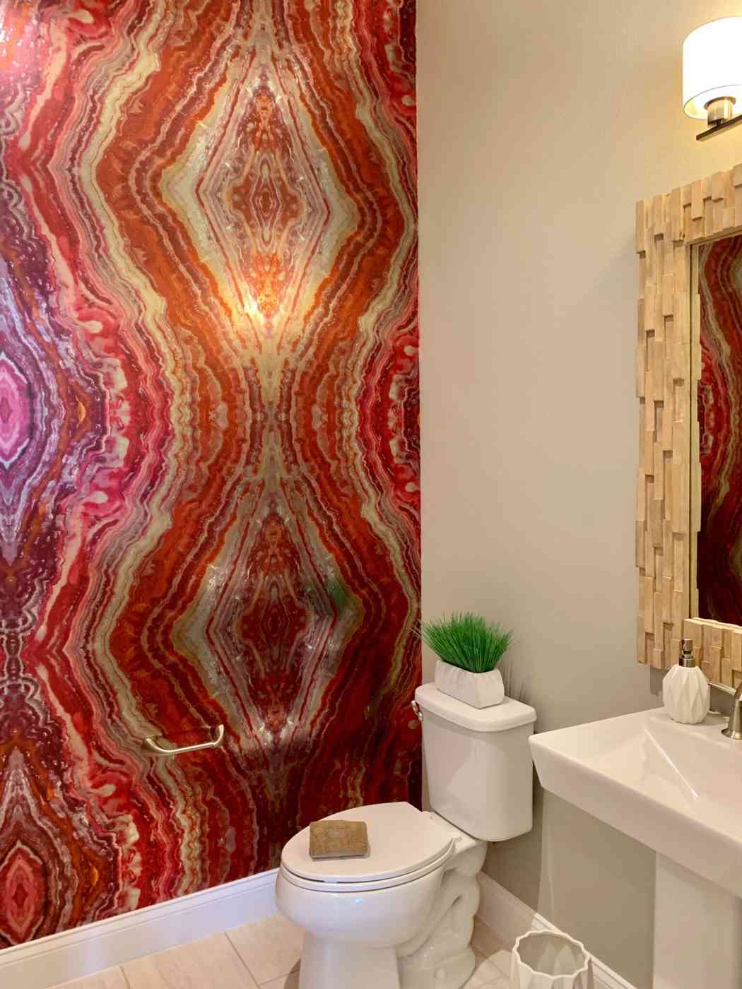 Luxurious bathroom with red agate patterned wallpaper and bold gold accents.