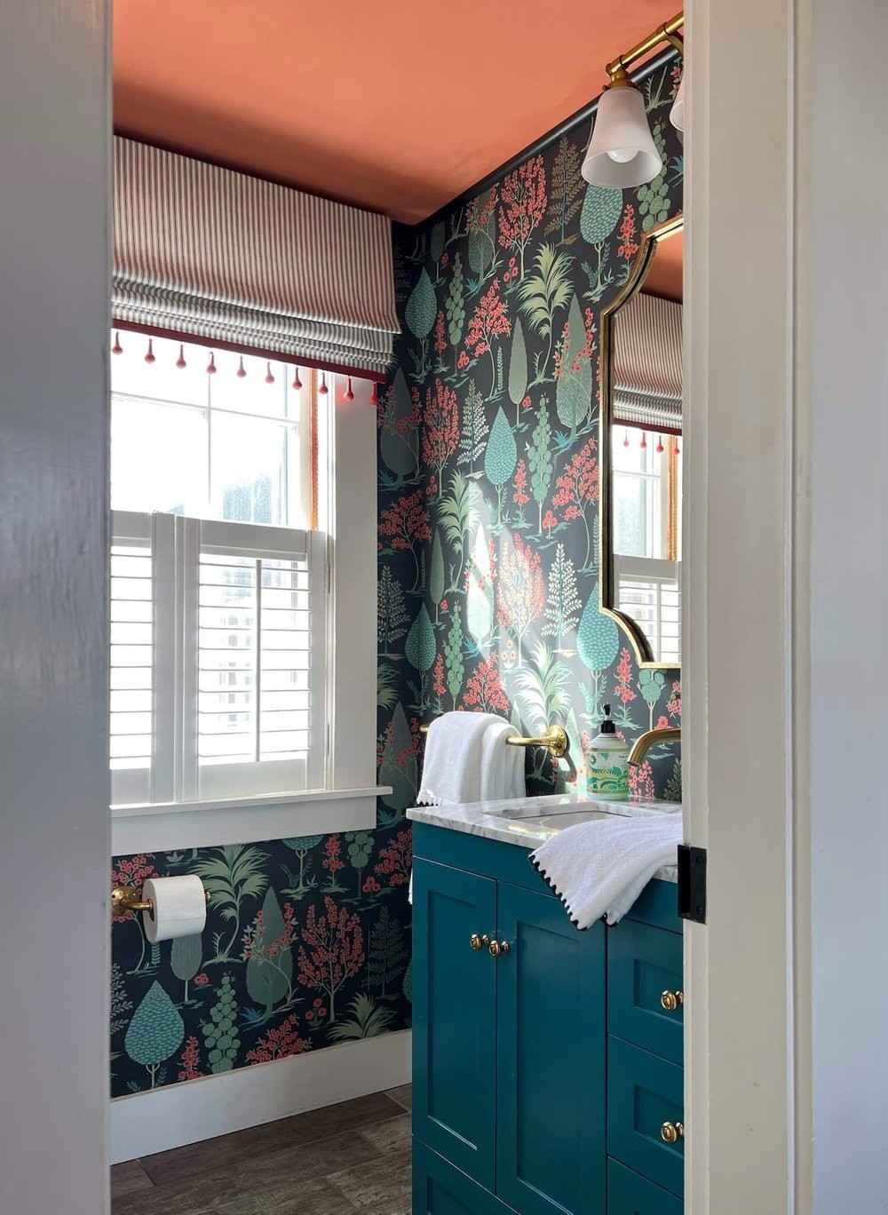 A moody and sophisticated powder room featuring deep teal floral wallpaper.