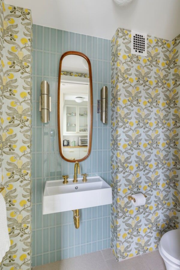 A bathroom vanity area featuring yellow floral wallpaper and a clean white vanity cabinet.