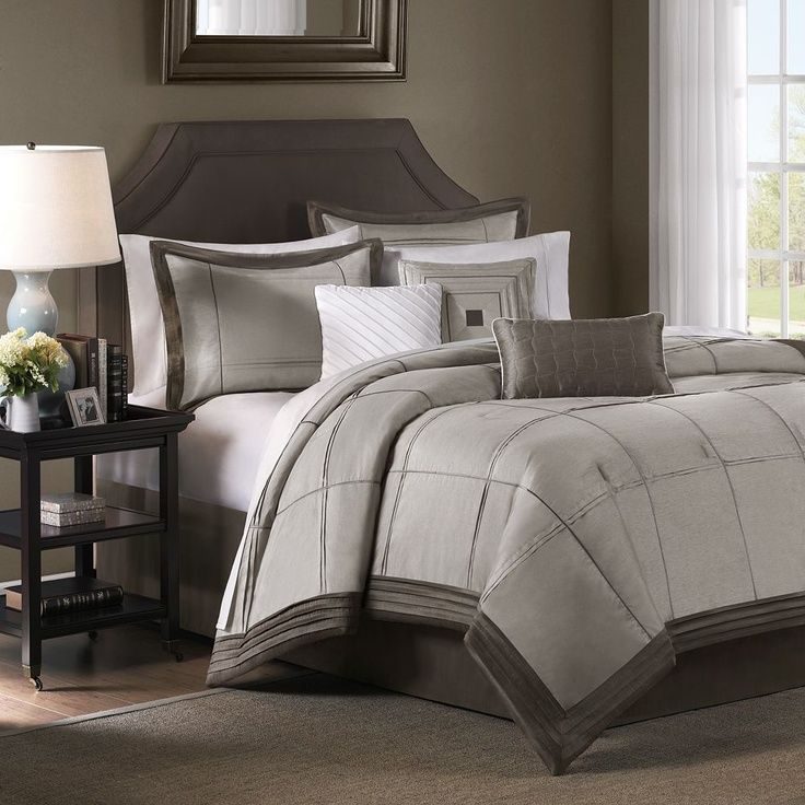 Coastal bedroom featuring dusty blue quilt set, crisp white linen sheets, natural woven rattan lighting, light wood floor