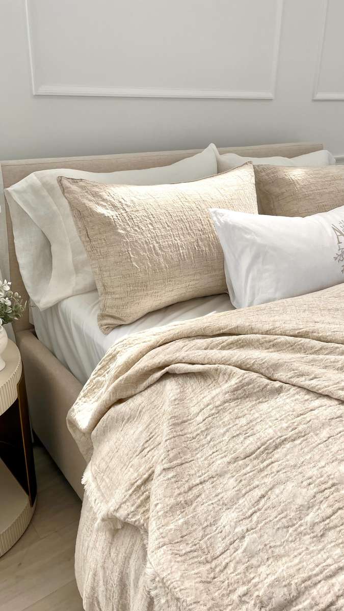 Cozy bedroom with oak bed frame, washed terracotta linen bedding, soft warm pendant lighting.