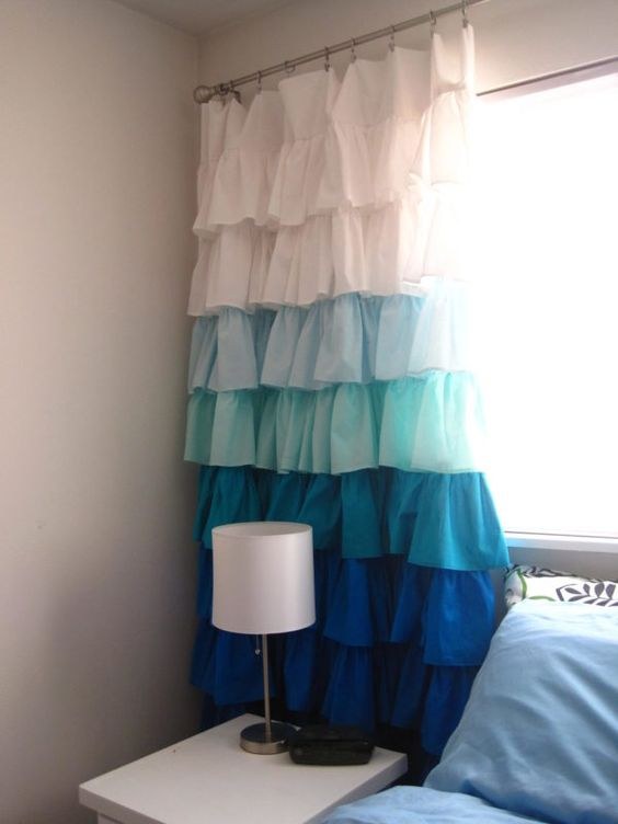 White ruffled bedroom curtains in a cozy cottage bedroom with floral bedding and wood floors.