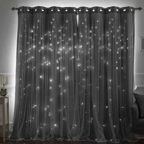 High-contrast patterned curtains in a modern bedroom with grey upholstered bed and gold lighting.