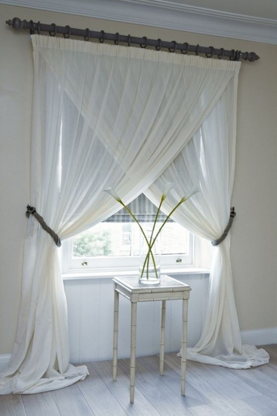 Dual-layer curtains with a sheer white layer and thick beige drapes in a neutral bedroom.